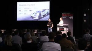 Two men stand on a stage at PMW Expo delivering a lecture