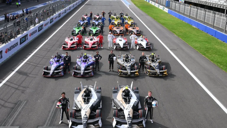 FIA and Formula E sign 10-year extension Formula E race cars line up on the grid with drivers standing beside their vehicles
