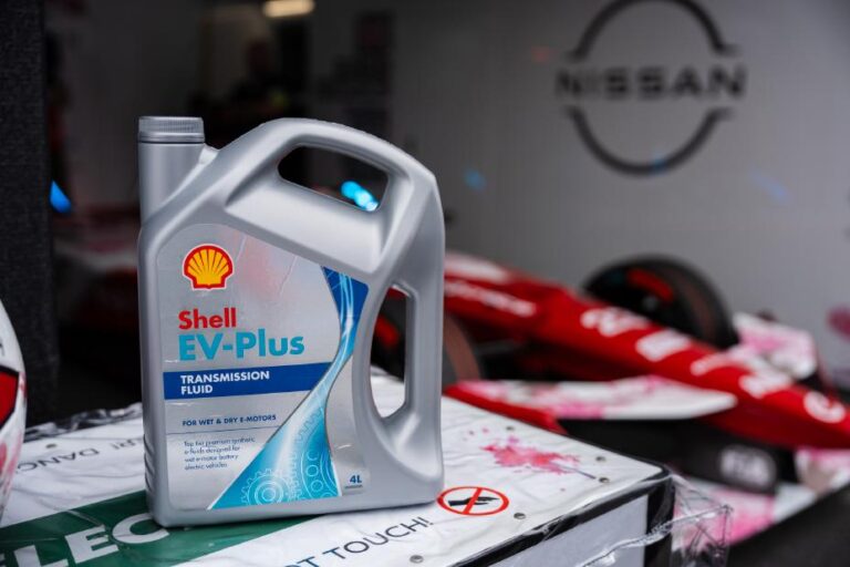 A carton of Shell EV-Plus automotive oil on the corner of a workstation in a garage.
