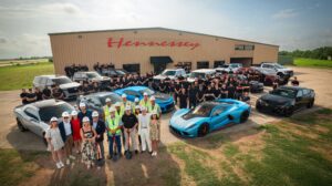 Hennessey staff and a range of the company's vehicles pose outside the front of a Hennessey building