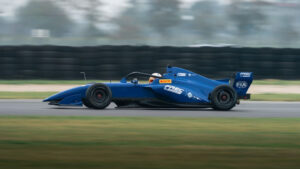 The Tatuus T-326 driving on a race circuit with the background blurred