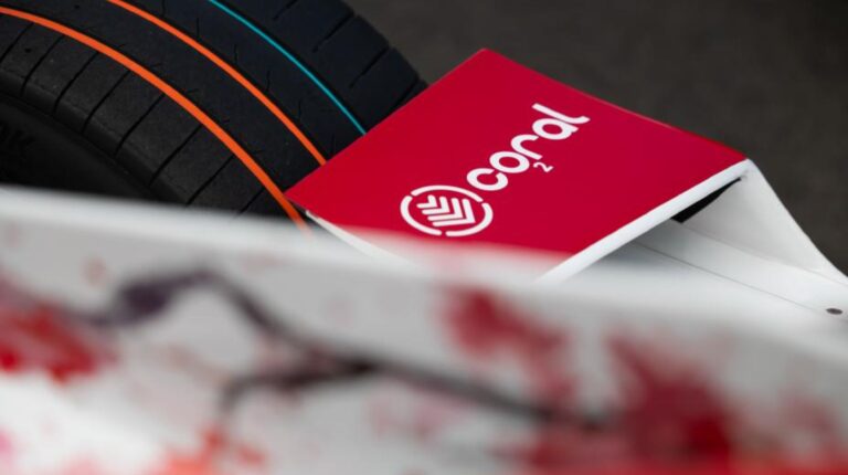 Red and white Coral logo in front of a black tire with orange, red and blue stripes along the circumference