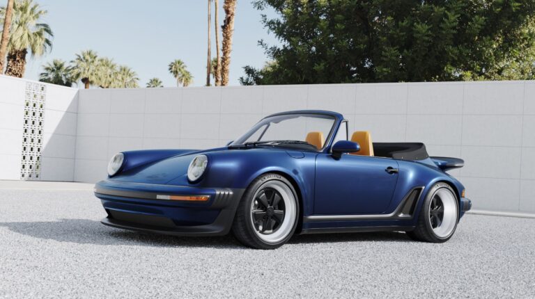 A blue, open-roof Porsche 911 Cabriolet parked on a grey empty parking lot.