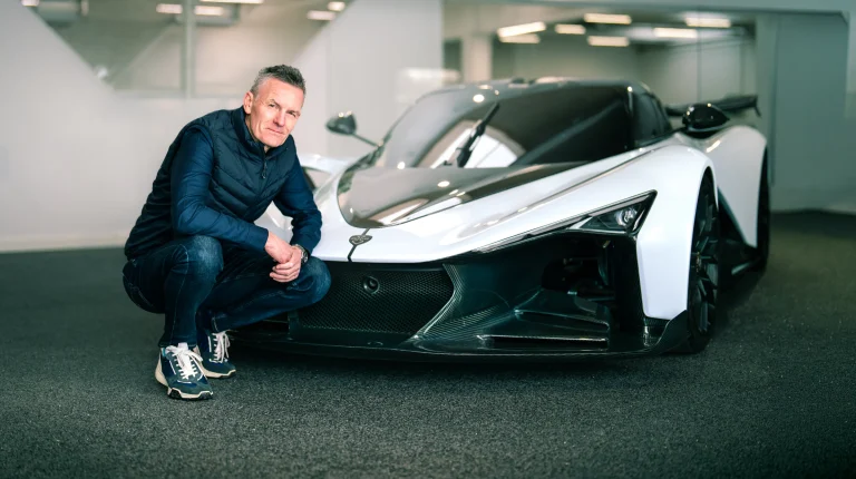 Mark Harrison, chief commercial officer at Zenvo Automotive, crouches next to a white hypercar.